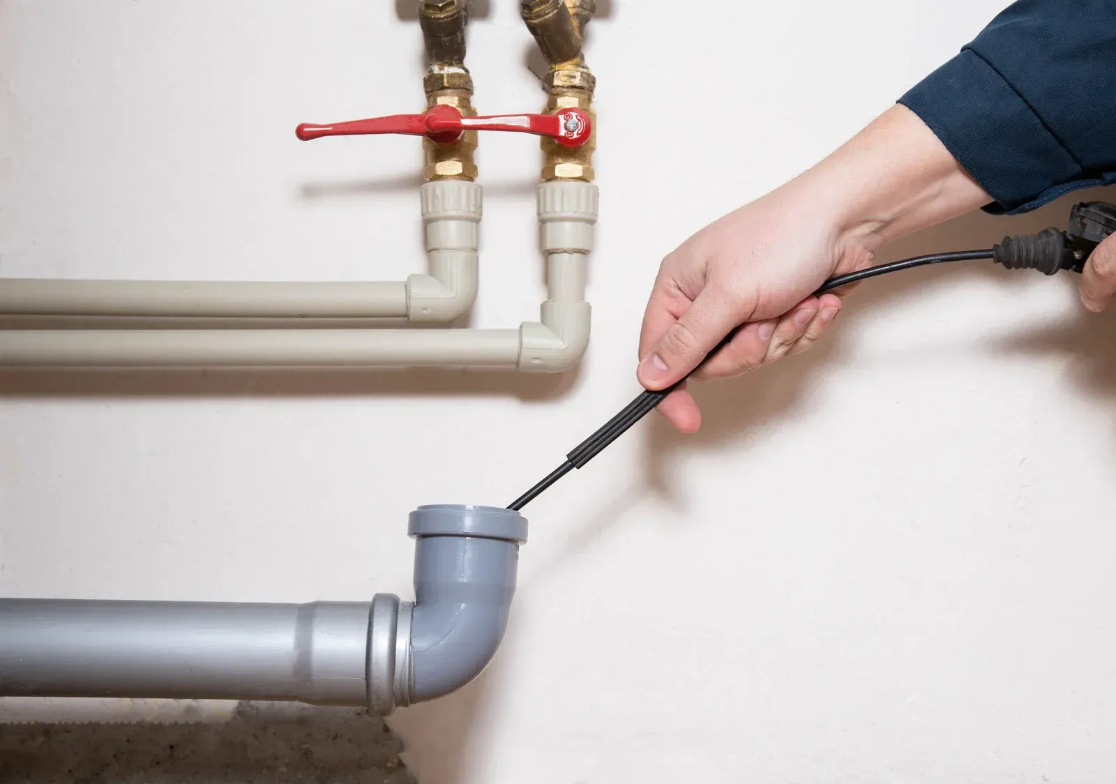 Plumber working under a kitchen sink, with tools and equipment visible.