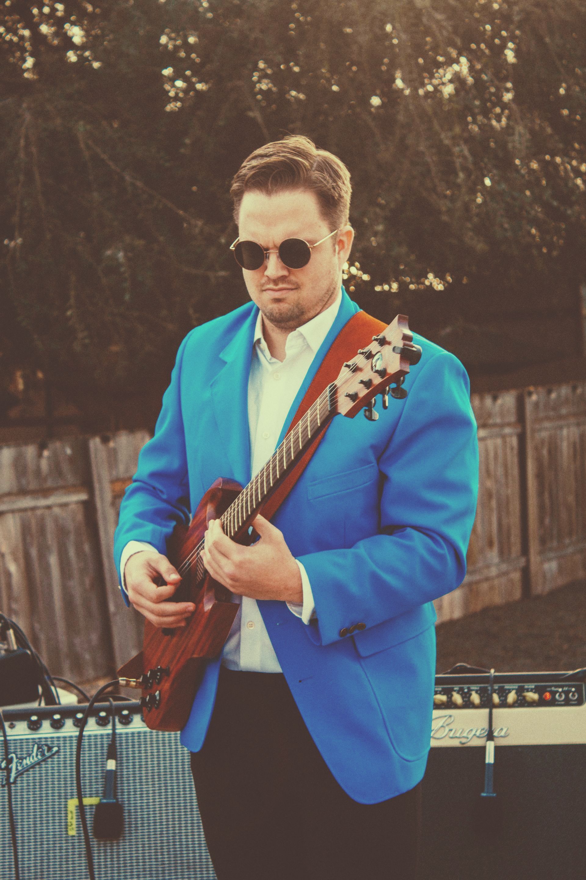 a man in a blue jacket is playing a guitar