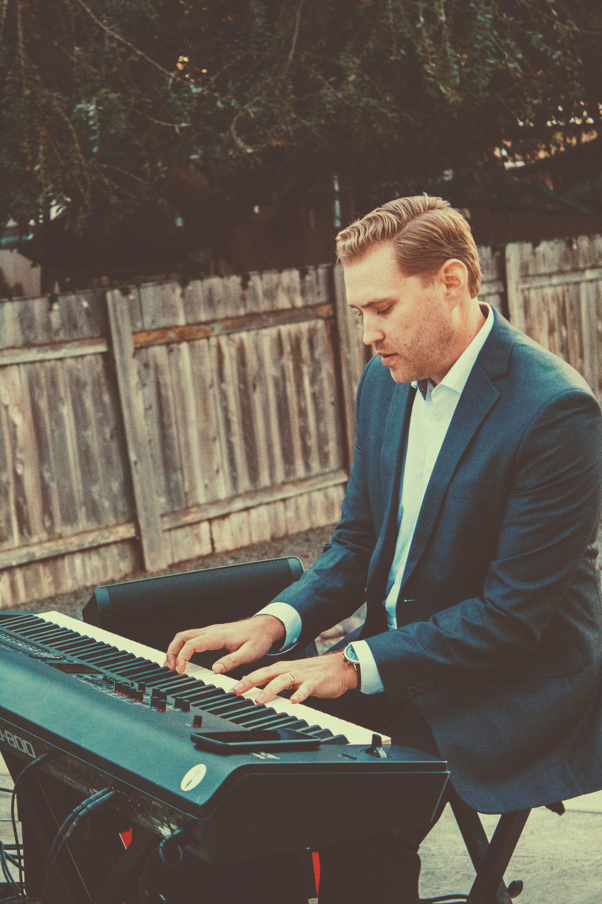 a man in a suit is playing a keyboard outside.