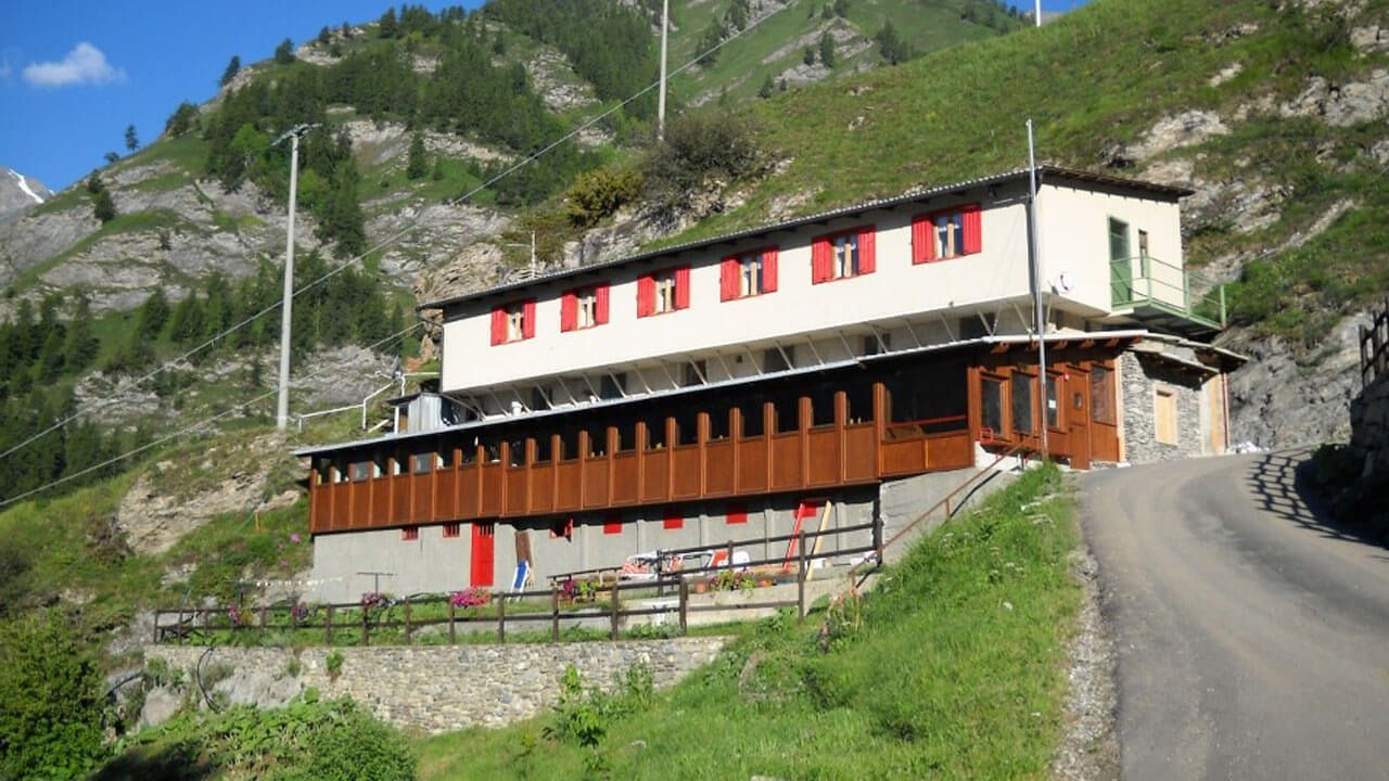 Un grande edificio si trova in cima a una collina, vicino a una strada.