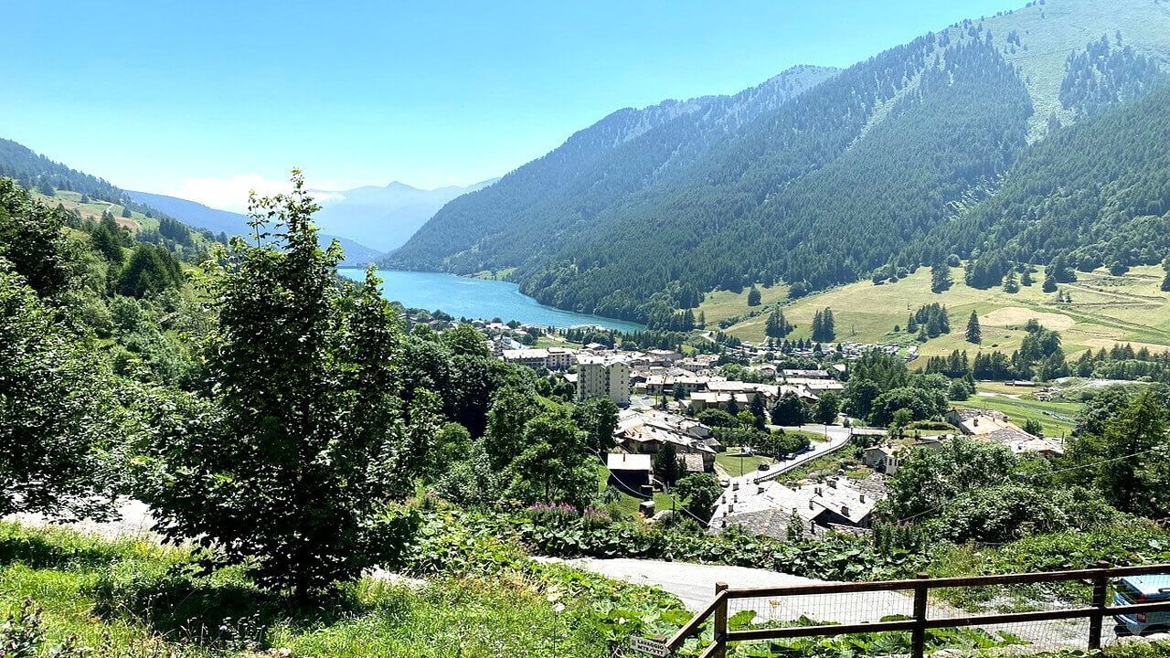 Una vista di un villaggio in montagna con un lago sullo sfondo.