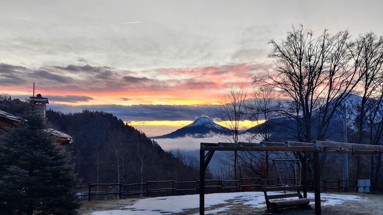 Un tramonto su una catena montuosa con un parco giochi in primo piano.