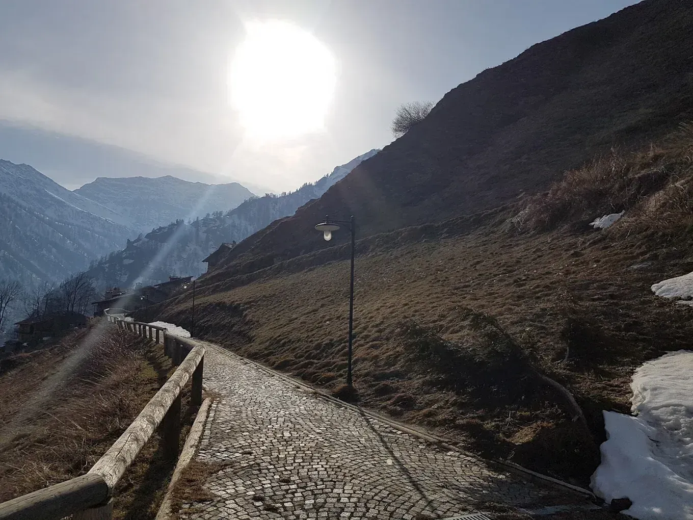 Un sentiero in montagna con il sole che splende tra le nuvole