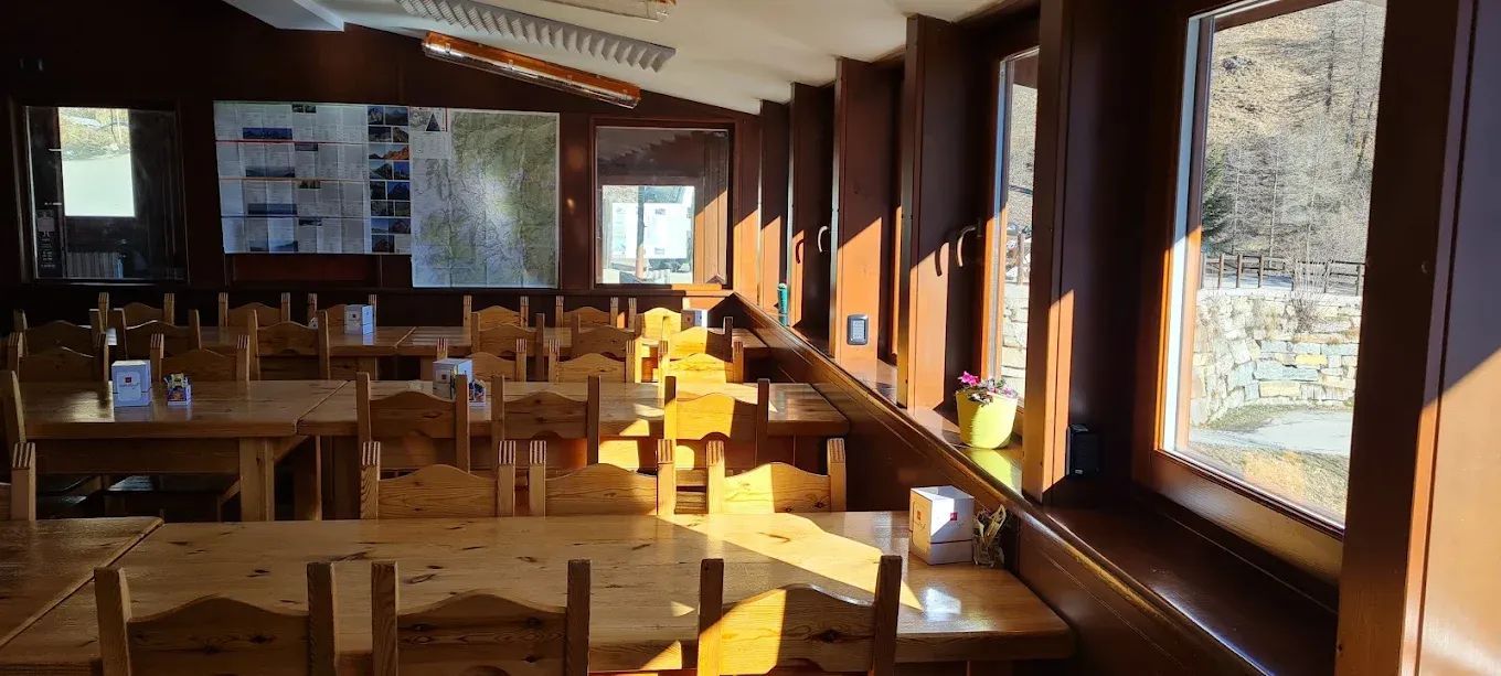 Una sala da pranzo con tavoli, sedie e numerose finestre.