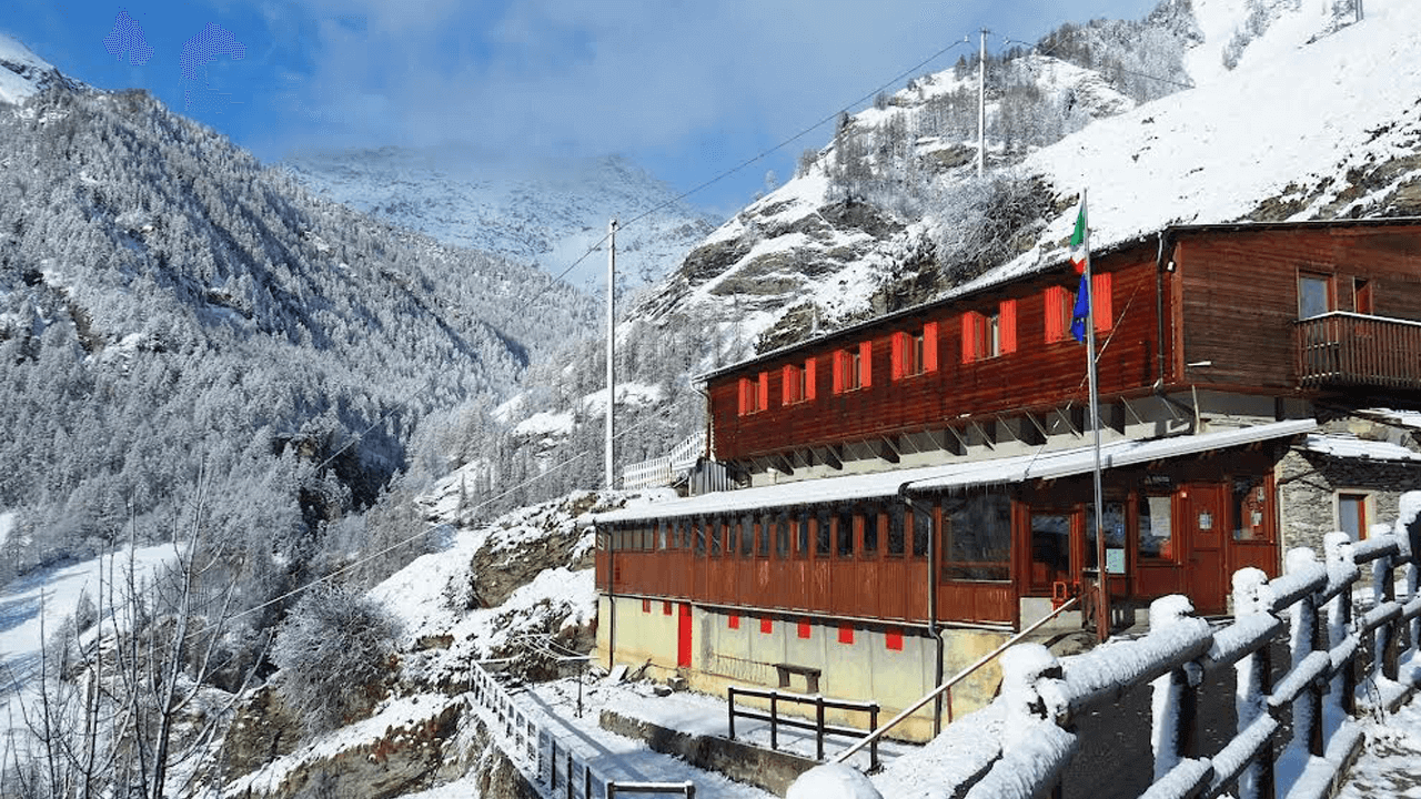 Un edificio rosso in mezzo a una montagna innevata.