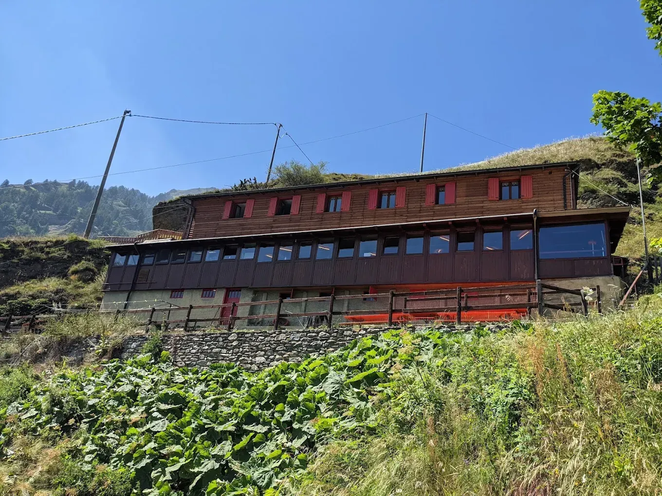 Un grande edificio in legno si trova in cima a una collina erbosa.