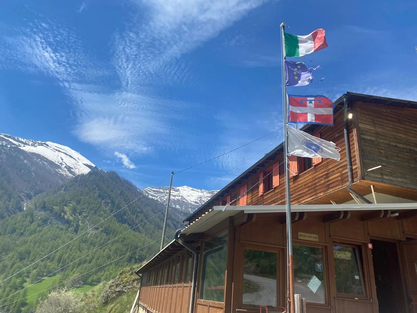 Un edificio in legno con bandiere che sventolano davanti e montagne sullo sfondo.