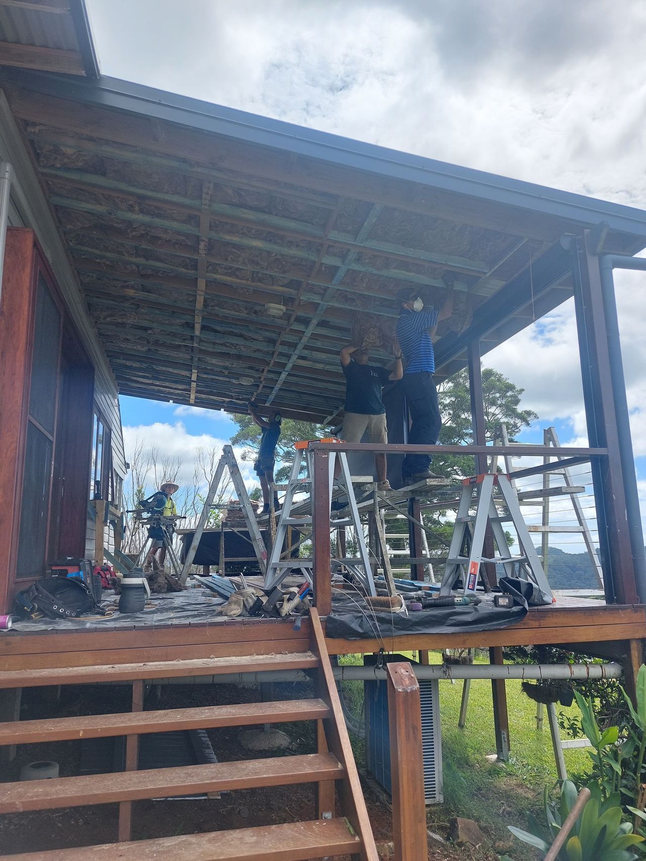 A group of people are working on a porch of a house.