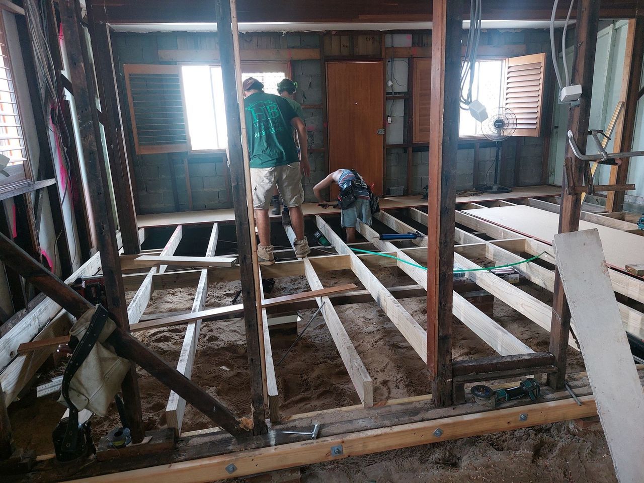 A group of people are working on the floor of a house.