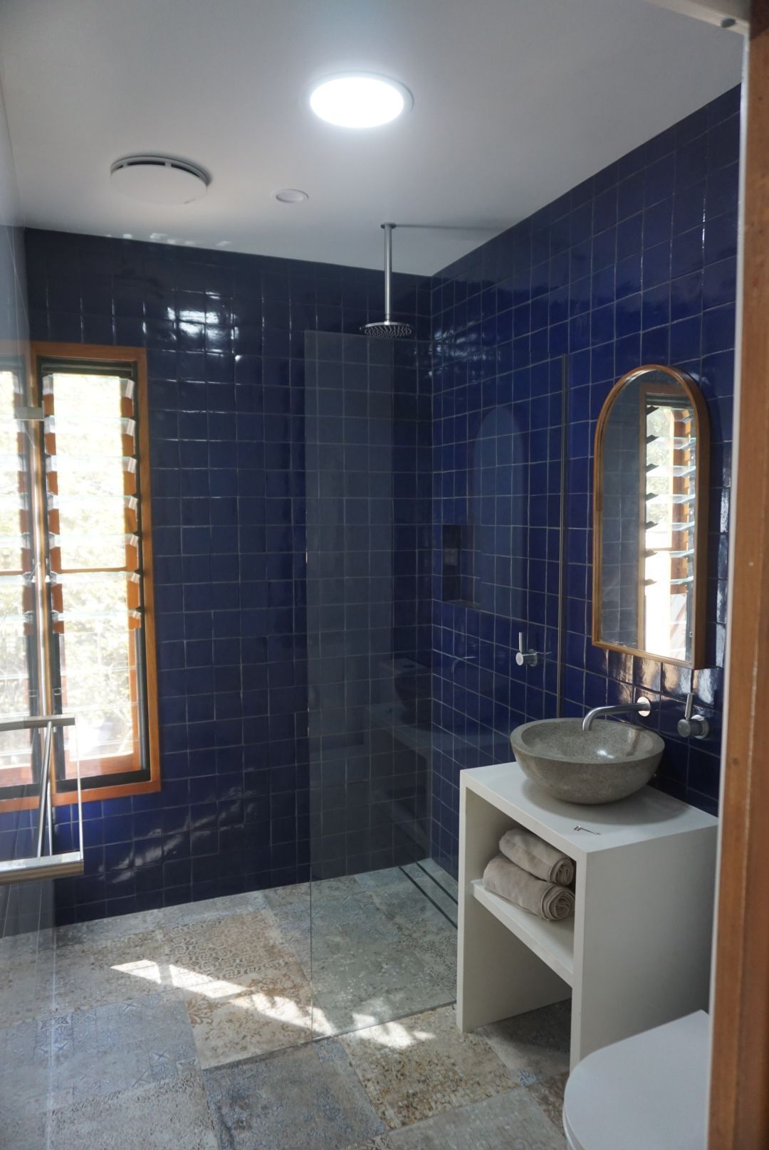 A bathroom with blue tiles and a sink and mirror