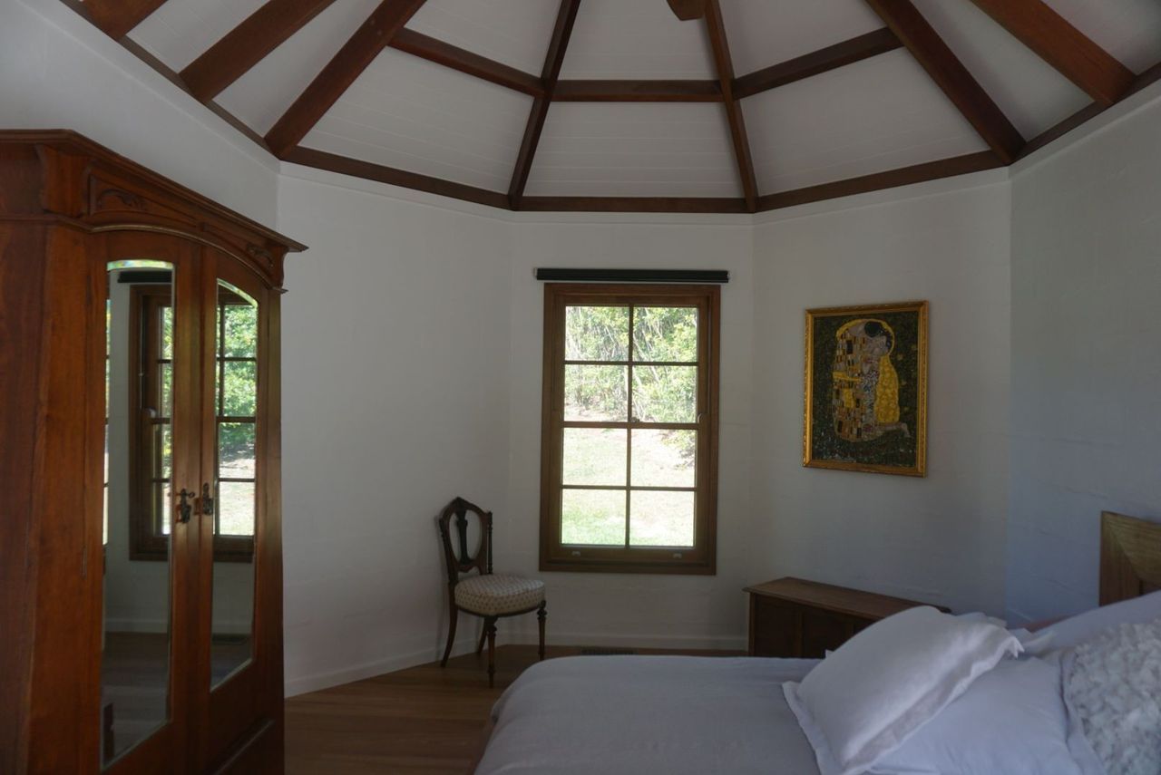 A bedroom with a bed , chair , wardrobe and a painting on the wall.