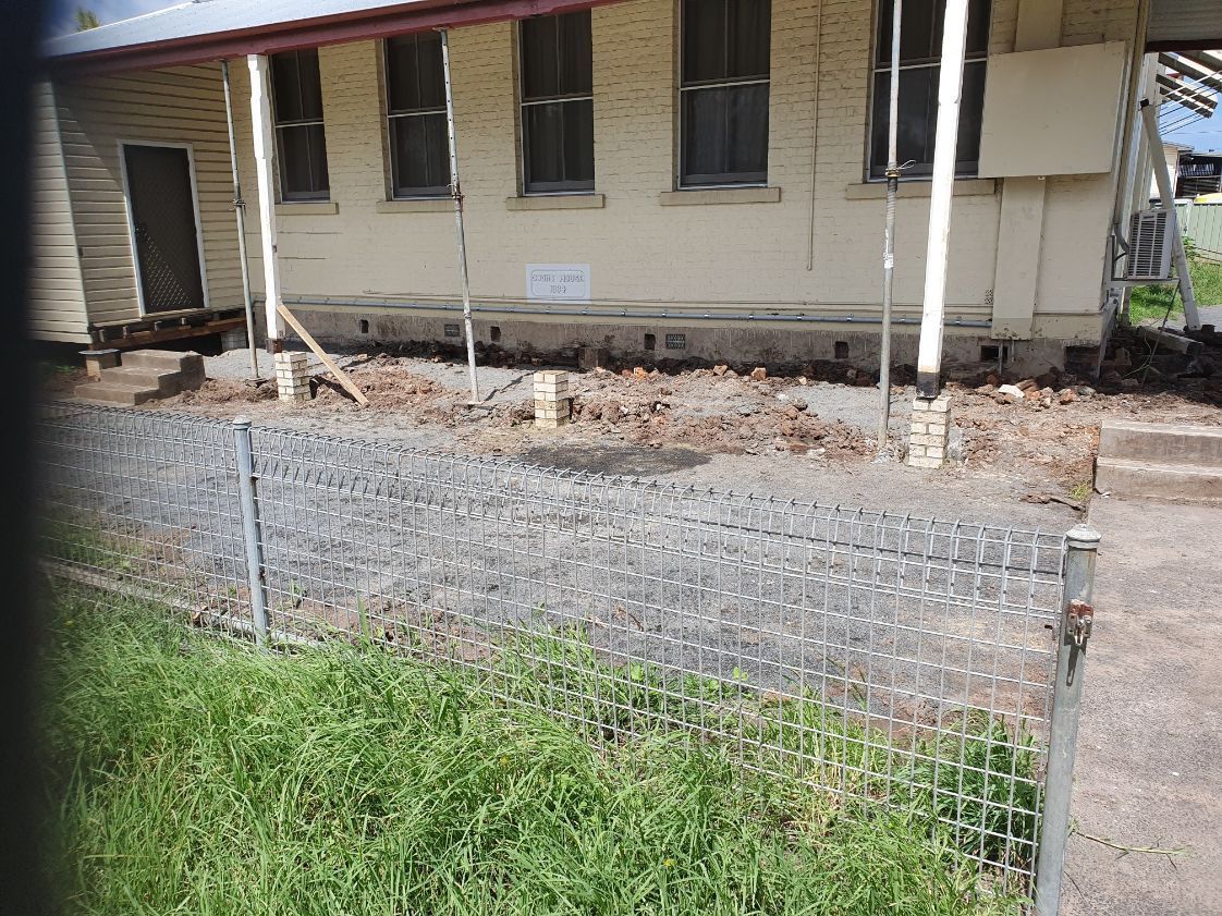 A house with a fence around it and a gravel driveway in front of it.