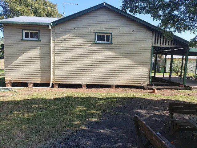 A white house with a green roof is sitting in the grass
