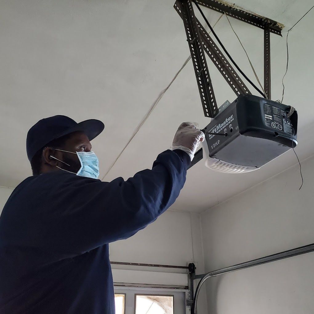 A man wearing a mask is working on a garage door opener