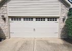 A white garage door is sitting in front of a brick house.