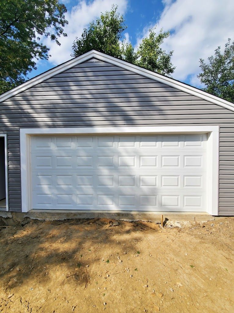A garage with a white garage door and a gray siding.