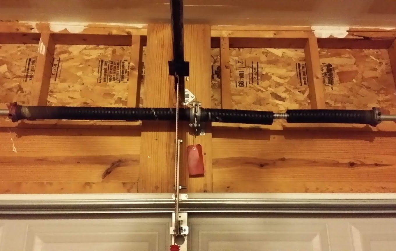 A garage door spring is hanging from the ceiling of a garage.