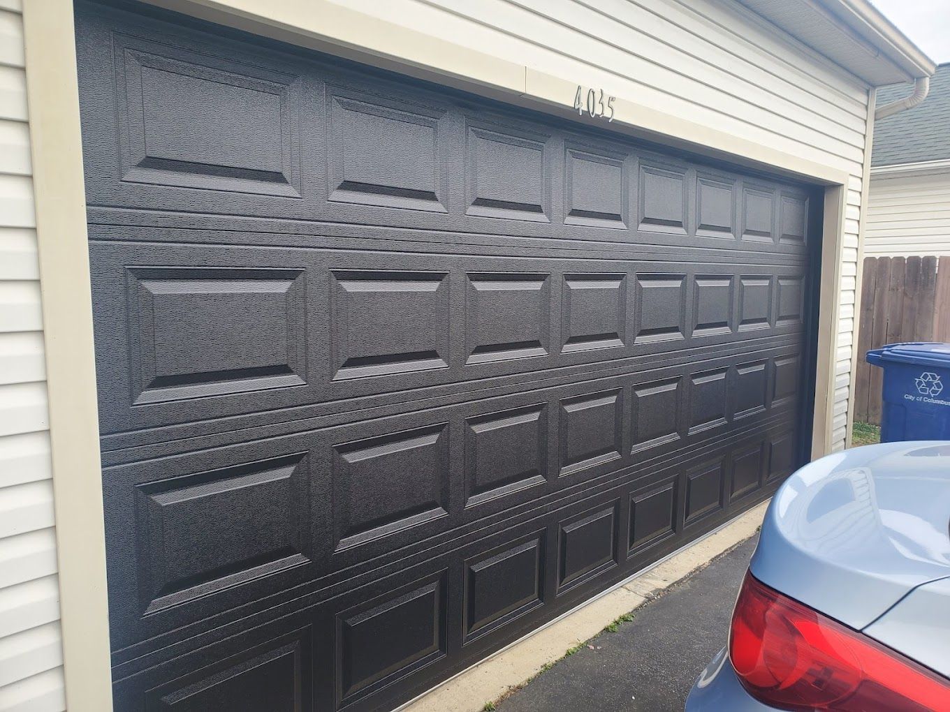 A car is parked in front of a black garage door.