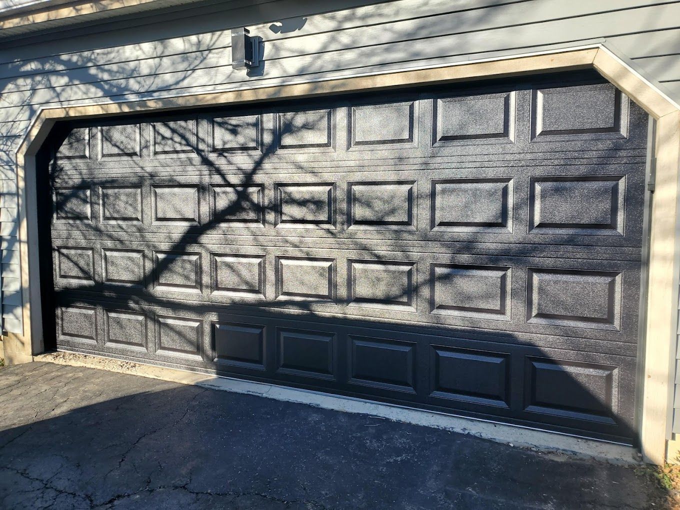 A black garage door is sitting in front of a house.