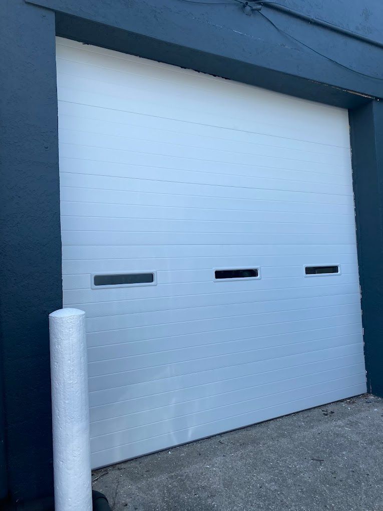 A white garage door is sitting in front of a blue building.