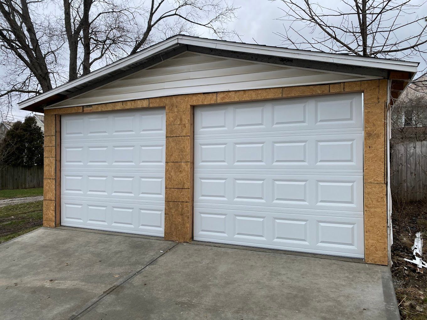 A garage with two white garage doors and a roof.
