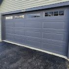 A gray garage door is sitting on the side of a house.
