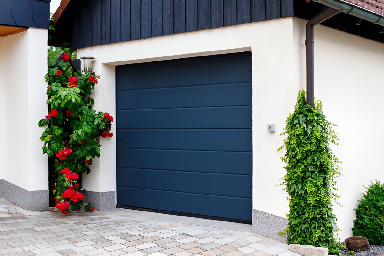A blue garage door is sitting in front of a white house.