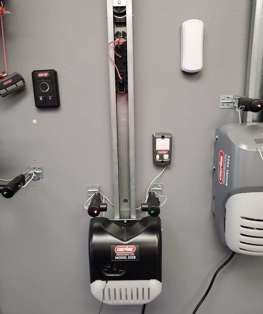 A garage door opener is hanging on a wall next to a remote control.