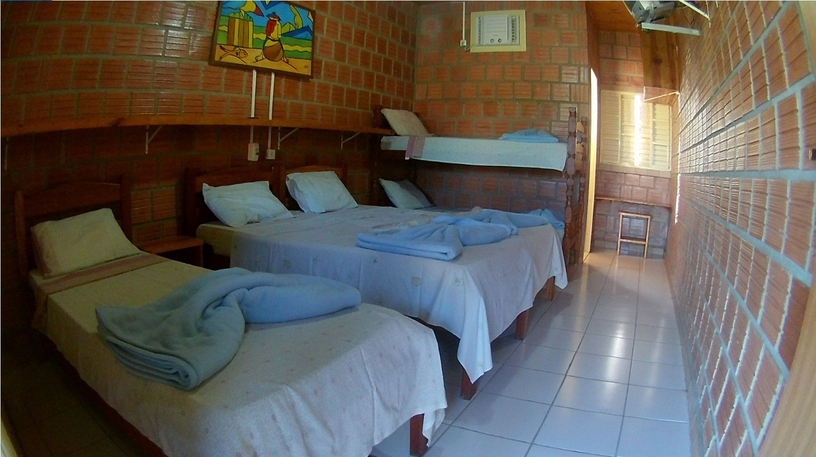 Um quarto com três camas e uma pintura na parede.