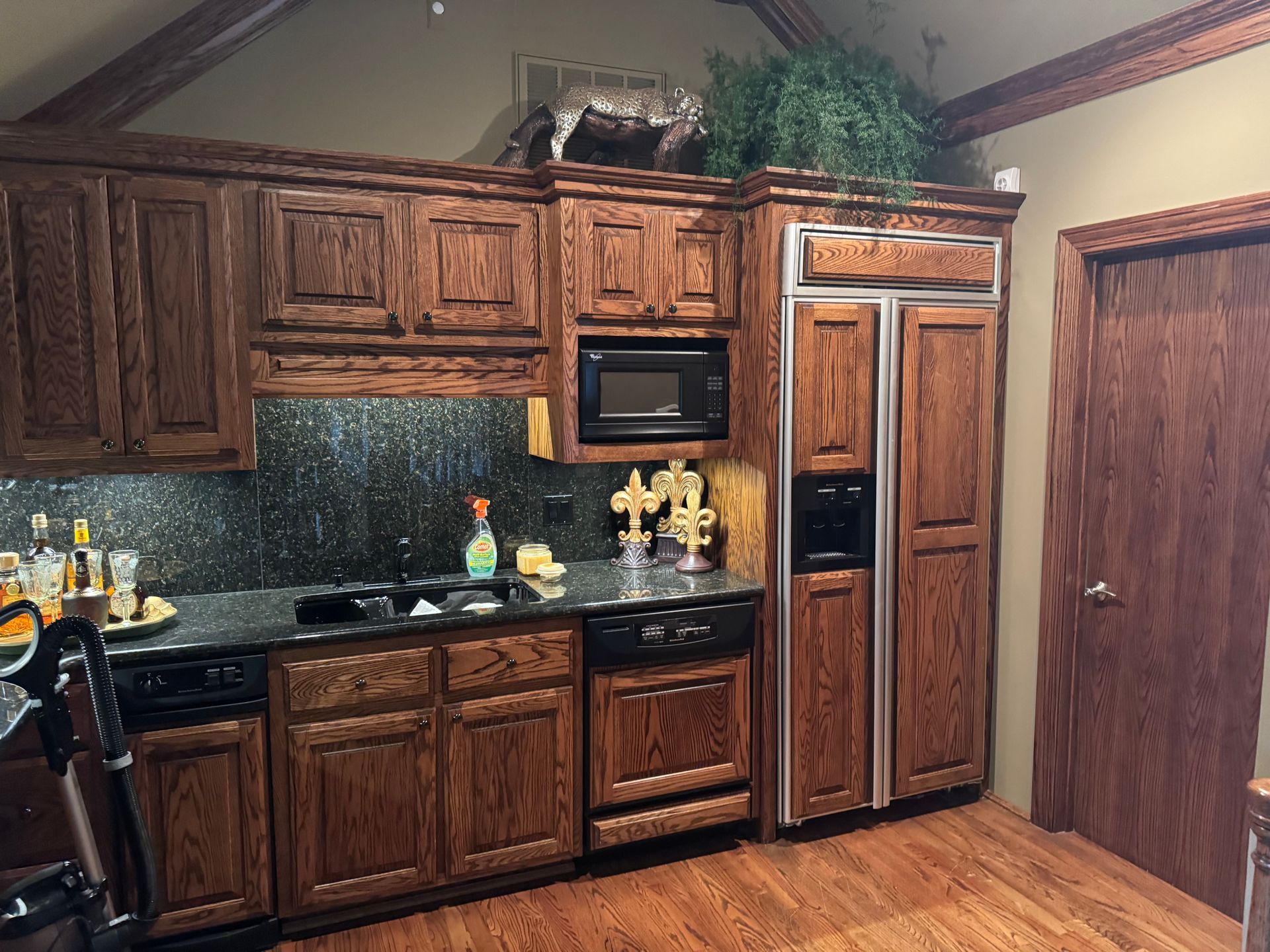 Wooden kitchen with dark cabinets, appliances, and a granite countertop.