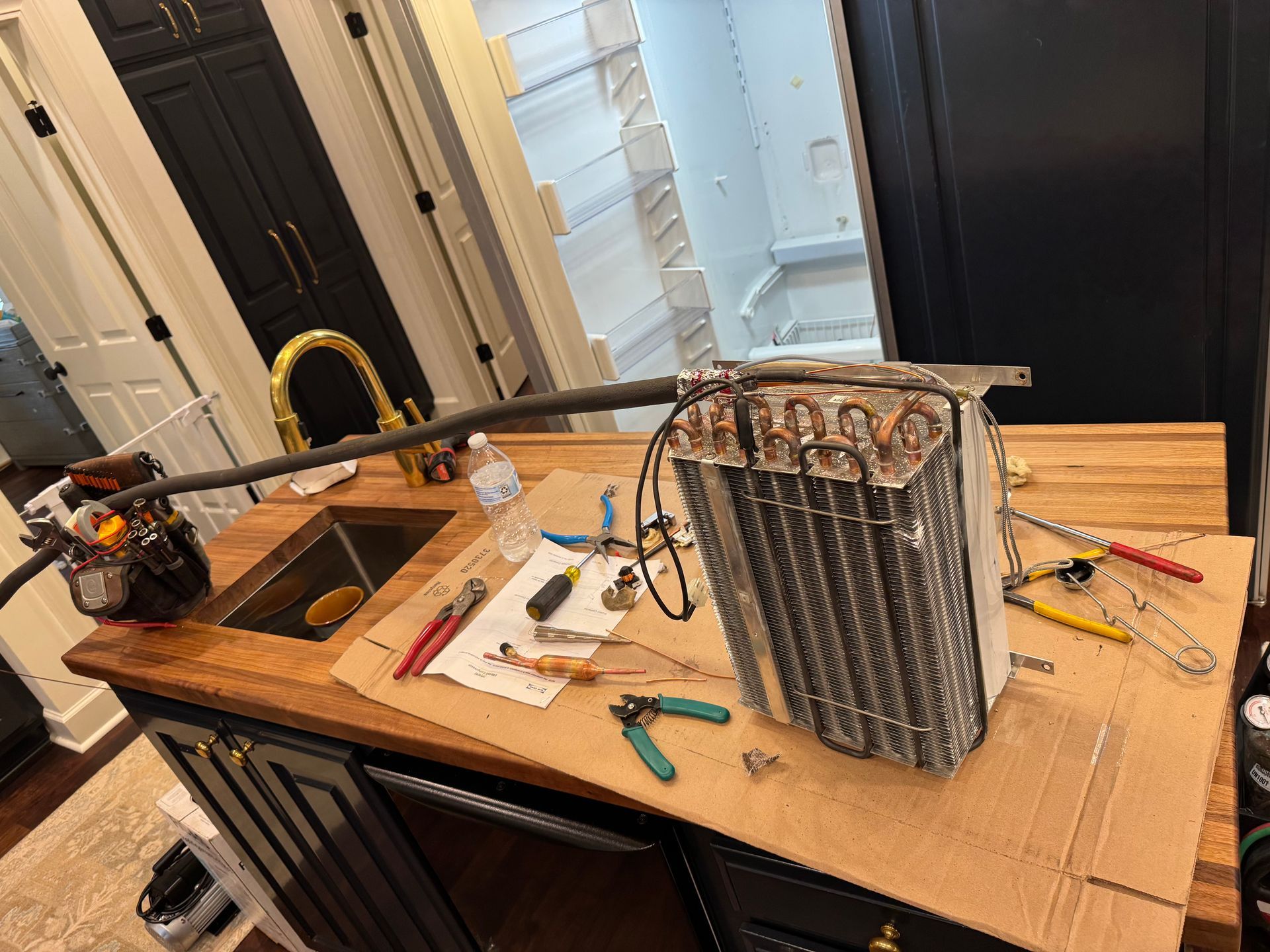 Refrigerator repair: technician works on evaporator coil on countertop with tools.