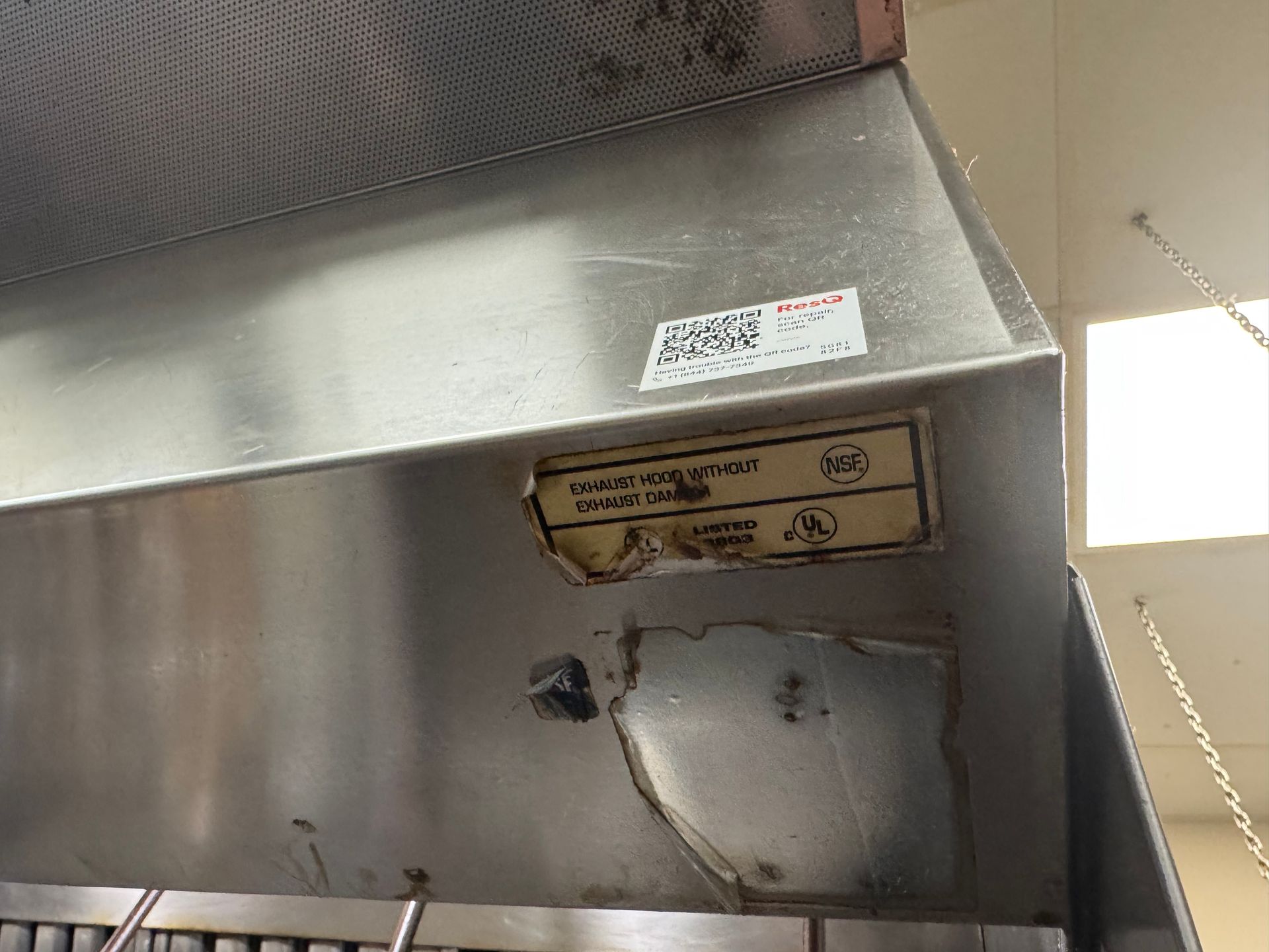 Stainless steel commercial kitchen hood with labels.
