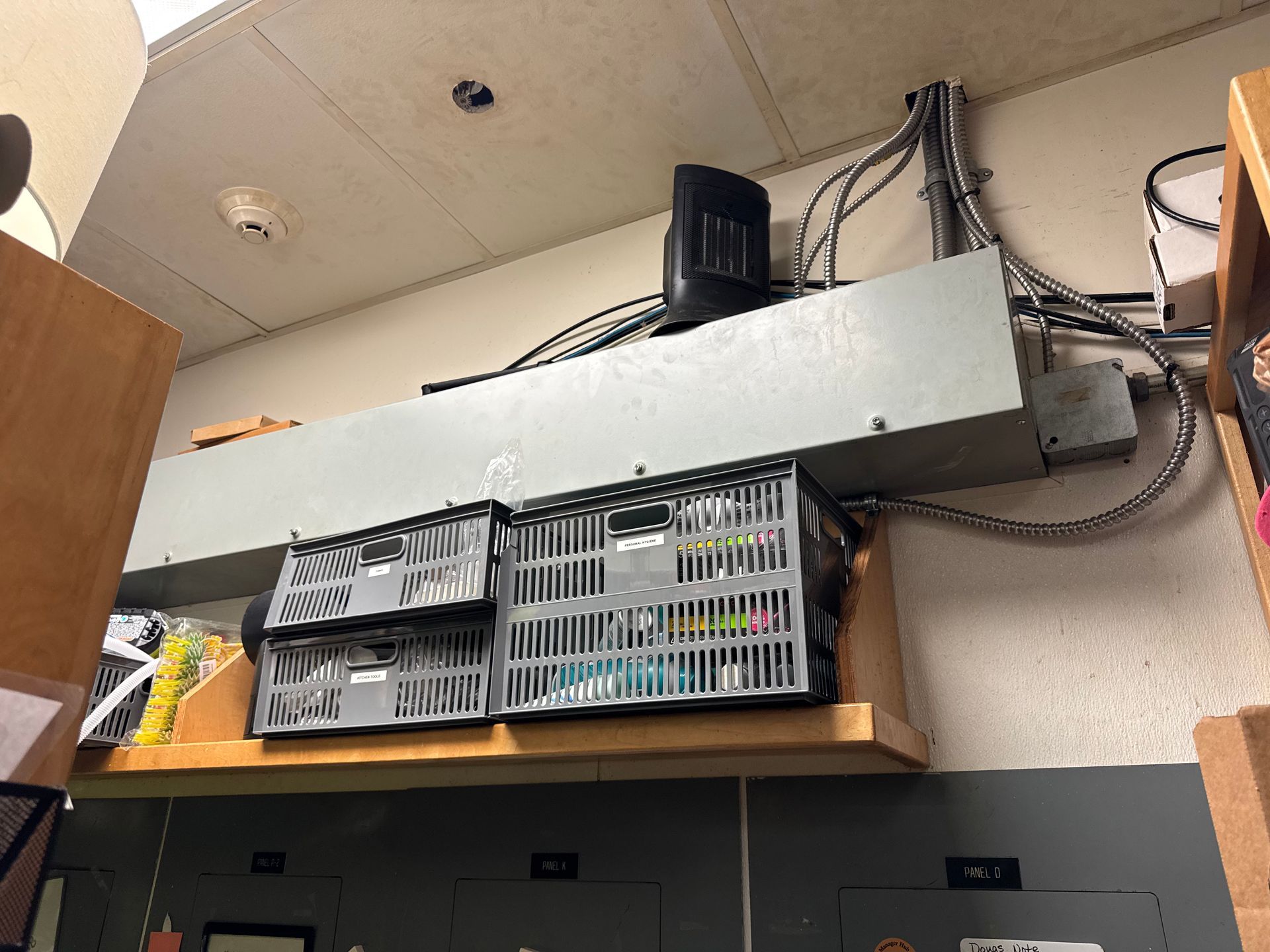 Cables, electrical box, and storage bins mounted on a shelf above a control panel.