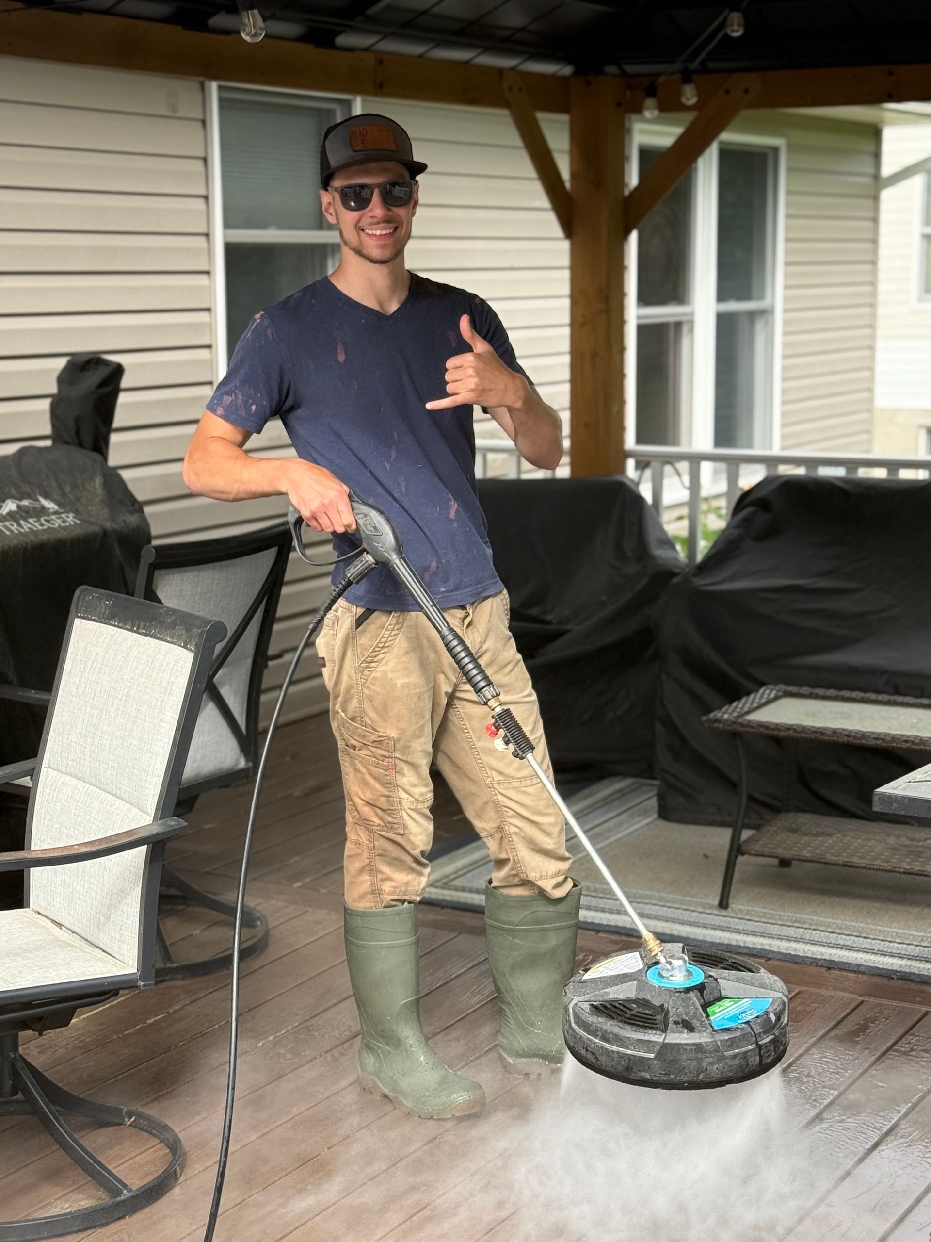 A man is using a hose to spray water on a deck. A man is using a hose to spray water on a deck.