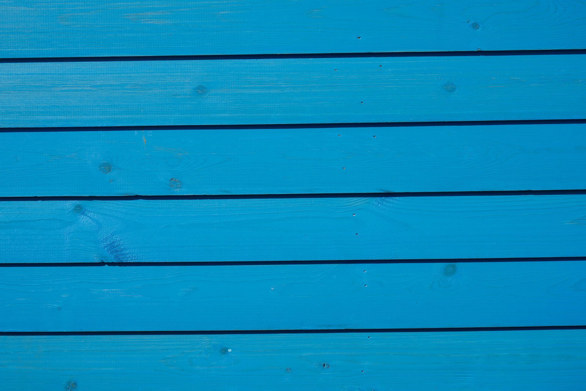 Blue wooden planks, horizontal, with shadows between each board.