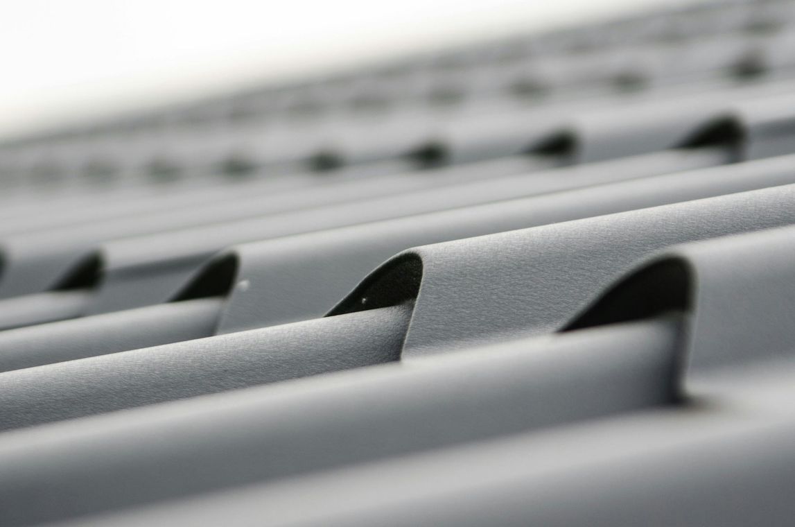 Close-up view of gray metal roofing with curved, wave-like edges.