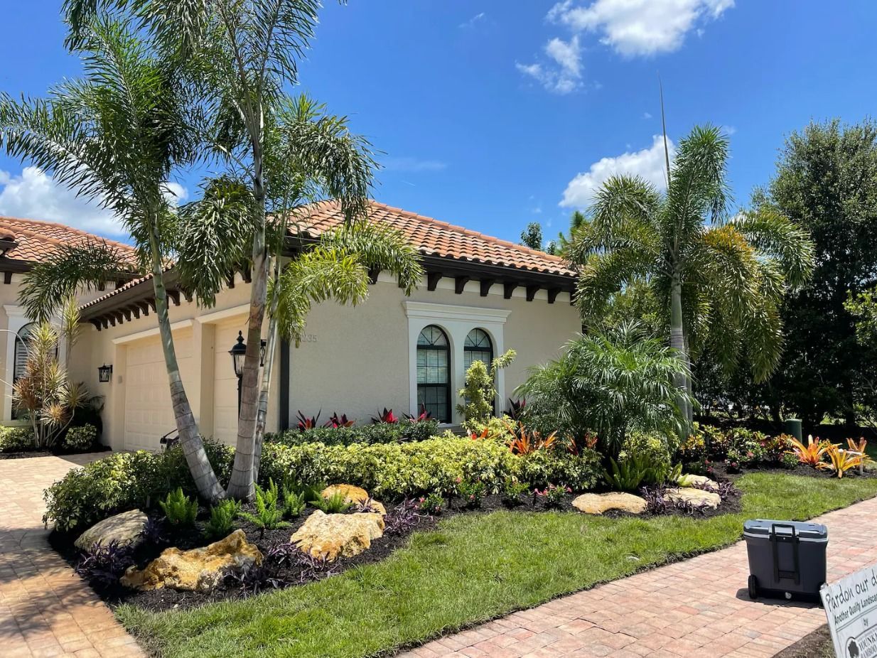 A large white house with a tile roof and a lot of trees in front of it.