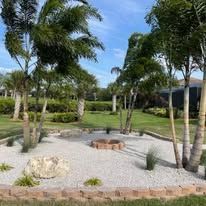 There is a fire pit in the middle of the garden surrounded by palm trees.