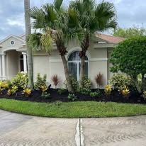 A house with palm trees in front of it and a lush green lawn.