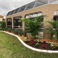 A large house with a screened in pool and a lush green lawn.