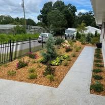 A sidewalk leading to a house with a garden in front of it.