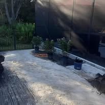 A patio with potted plants and a fence in the background.