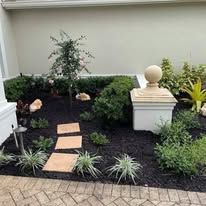 A garden with a brick walkway leading to a statue in the middle of it.
