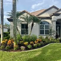 A white house with a lot of plants in front of it.