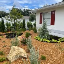 A white house with red shutters and a garden in front of it.