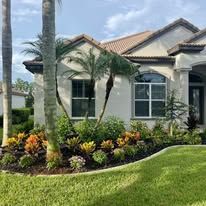 A white house with a lot of plants in front of it.