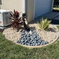 A garden with rocks and plants in front of a house.