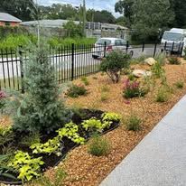 A fenced in yard with lots of plants and flowers.