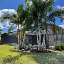 A house with a screened in porch and palm trees in front of it.