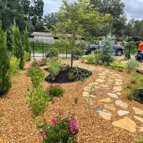 A lush green garden with a stone path and trees.